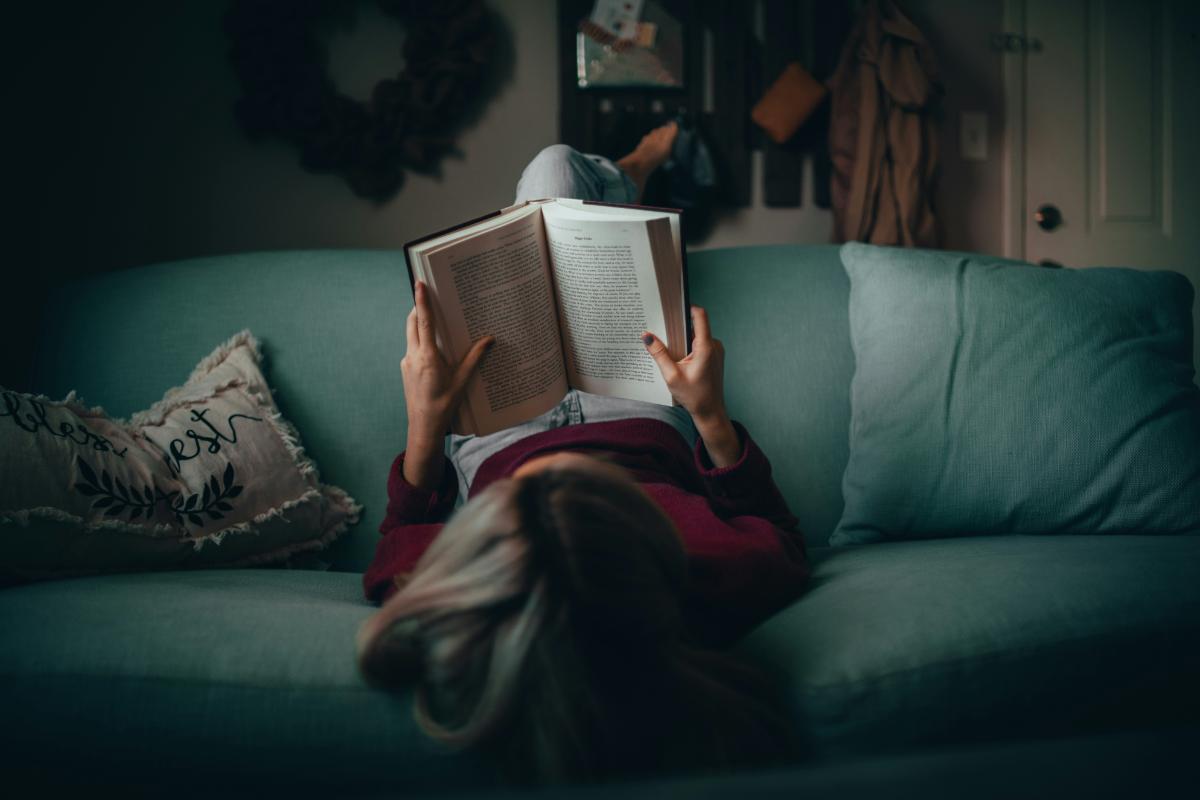 Persona recostada en un sillón, leyendo